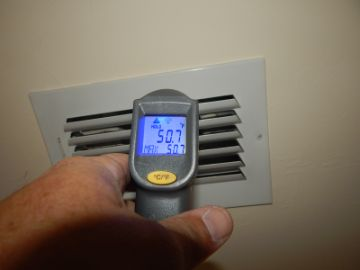 Thermometer measuring air temperature at an HVAC vent