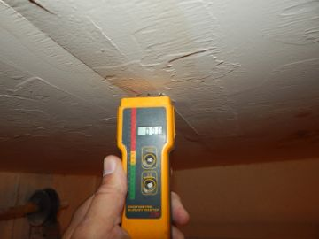 Moisture meter testing a stained ceiling